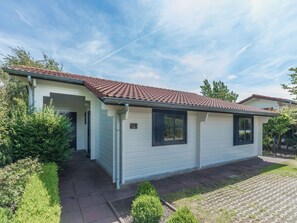 A single-story house with a tiled roof, a covered porch, and a well-maintained lawn. - Holiday Home in Renesse With Swimming Pool (Renesse)