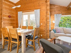 A wooden interior with a dining table, chairs, a sofa, and a window with curtains. - Holiday Home in Renesse With Swimming Pool (Renesse)