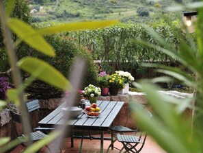 An outdoor patio with a table and chairs, surrounded by potted plants and a view of a lush landscape. - L"ea di Lavru - Apt 10 (Loiri Porto San Paolo)