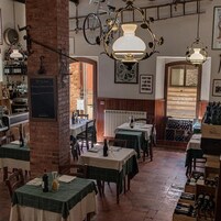 Interior de restaurante con paredes de ladrillo, mesas de madera y luces de bicicleta colgantes.