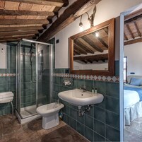 Un baño con cabina de ducha de vidrio, un bidé y un lavamanos con espejo.