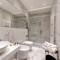 Un baño moderno con ducha envuelta en vidrio, un bidé y un lavamanos con lavabo y espejo.