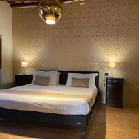 Un dormitorio con una cama grande, dos mesitas de noche y una lámpara fijada a la pared.