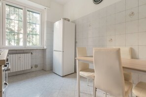 Eine Küche mit Kühlschrank, einem Fenster und einem Esstisch mit Stühlen.