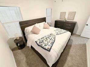 Een slaapkamer met een bed, nachtkastjes, een kaptafel en een deur.