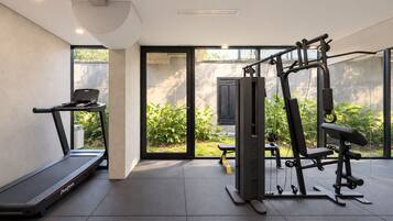 Un gimnasio moderno en casa con cinta de correr, banco de pesas y equipo de ejercicio multifuncional.