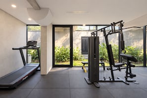 A modern home gym with a treadmill, weight bench, and multi-functional exercise equipment. - Palermo Design Apartments by BueRentals (Buenos Aires)