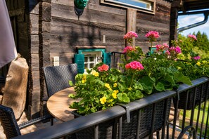 Ein hölzernes Gebäude mit Fenster und Tür, einem Tisch mit Stühlen und einem Blumenkasten mit Blumen.