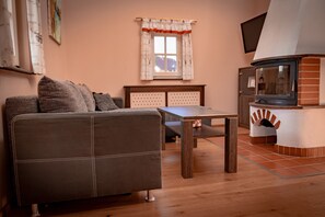 Ein Wohnzimmer mit einer Couch, einem Holztisch, einem Fernseher und einem Kamin.