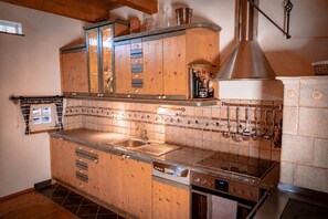 A kitchen with wooden cabinets, a stainless steel sink, and a built-in oven. - Holiday Home 'Traumhaftes Winzerhäuschen' with Mountain View, Private Terrace and Wi-Fi (Sulb)