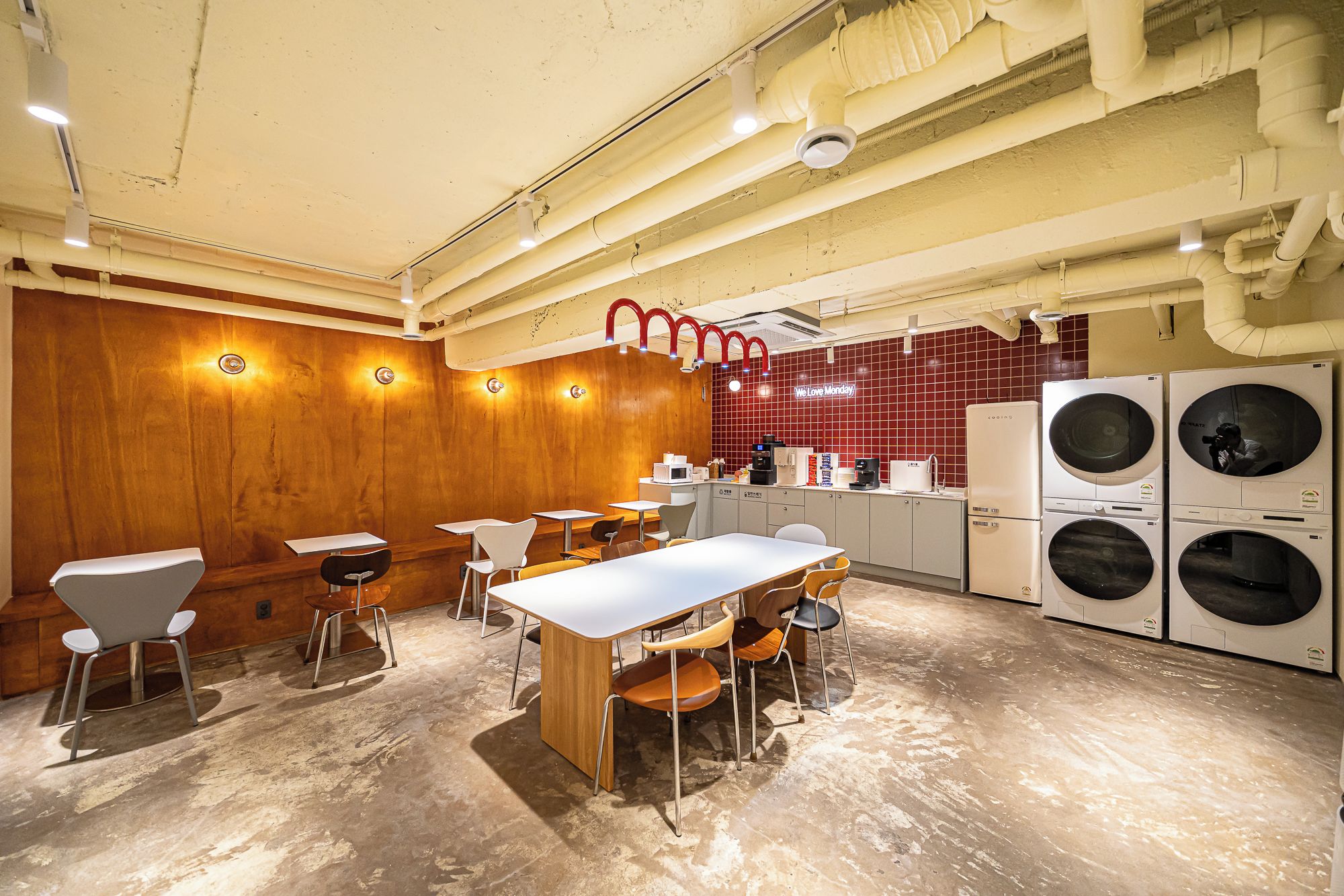 A modern kitchen with built-in appliances, wooden walls, and a seating area with tables and chairs.