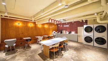 A modern kitchen with built-in appliances, wooden walls, and a seating area with tables and chairs.