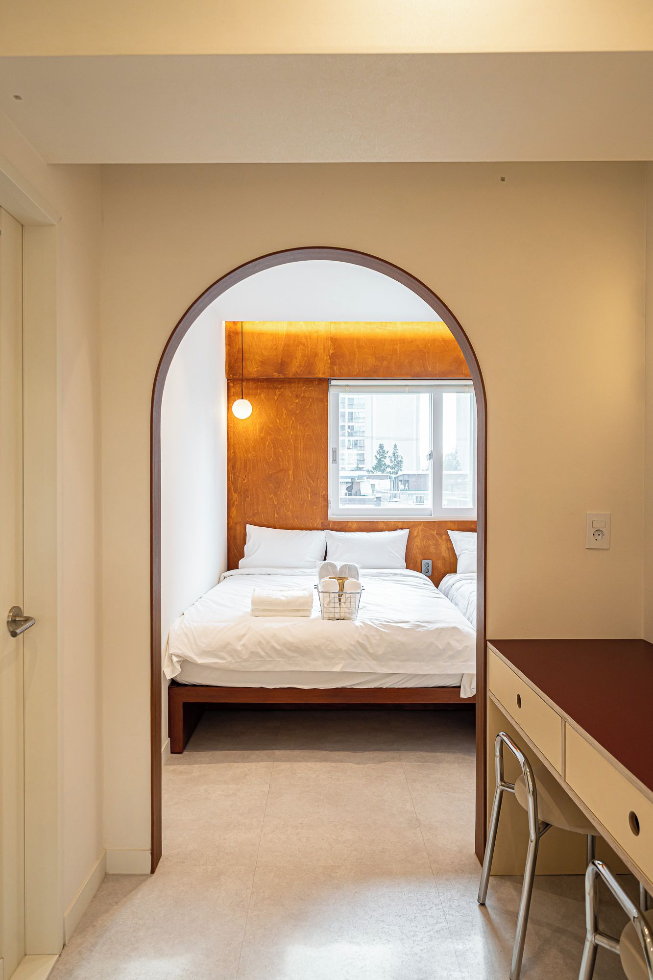 A bedroom with a bed, a desk, and a window.