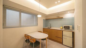 A compact kitchen with a dining area, featuring a microwave, a sink, and a small refrigerator.