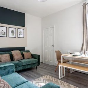 A modern living room with a green sofa, a wooden coffee table, and a patterned rug. - Darlington - House - Central Location - Sleeps 6 (Darlington)