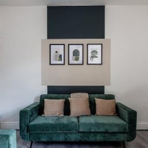 A green sofa with three cushions against a wall with three framed artworks. - Darlington - House - Central Location - Sleeps 6 (Darlington)