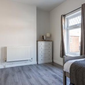 A bedroom with a bed, a dresser, a radiator, and a window. - Darlington - House - Central Location - Sleeps 6 (Darlington)