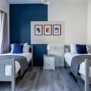 Una habitació d'hotel amb dos llits, una tauleta de nit i una paret amb tres quadres.
