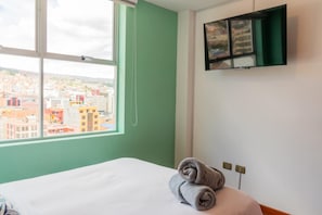 A hotel room with a bed, a window with a city view, and a wall-mounted TV. - 29296295 (La Paz)