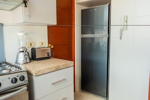 A kitchen with a gas stove, a blender, a toaster, and a refrigerator. - 29296295 (La Paz)