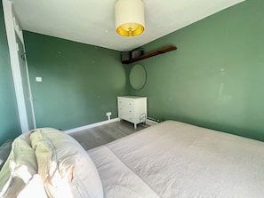 Ein Schlafzimmer mit einem Bett, einem Schminktisch, einem Nachttisch und einer Hängelampe.