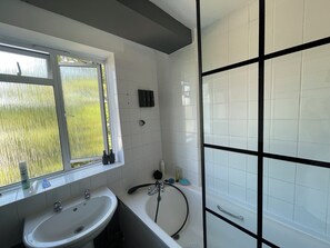 Un baño con ventana, lavabo, bañera y zona de ducha.