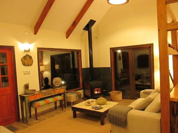A cozy living room with a fireplace, a sofa, a coffee table, and a bench. - Parador Loberias del Sur Puerto Bertrand (Chile Chico)