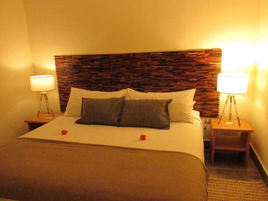A hotel room with a bed, two bedside lamps, and a wooden headboard.