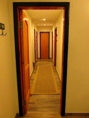 A hotel hallway with carpeted floors, wooden doors, and a carpet runner. - Parador Loberias del Sur Puerto Bertrand (Chile Chico)