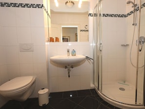 A bathroom with a toilet, sink, and glass-enclosed shower. - 7 Residence Bismarck (Sylt)