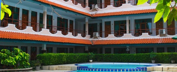 A multi-story building with balconies, a swimming pool, and greenery. - Fortuna Hotel Pangandaran (Pangandaran)