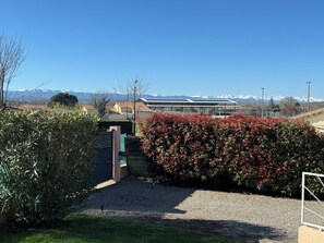 A building with a solar panel array, a gravel driveway, and a hedge with red flowers. - Villa on the ramparts with a terrace and a view of the Pyrenees (Montaut)