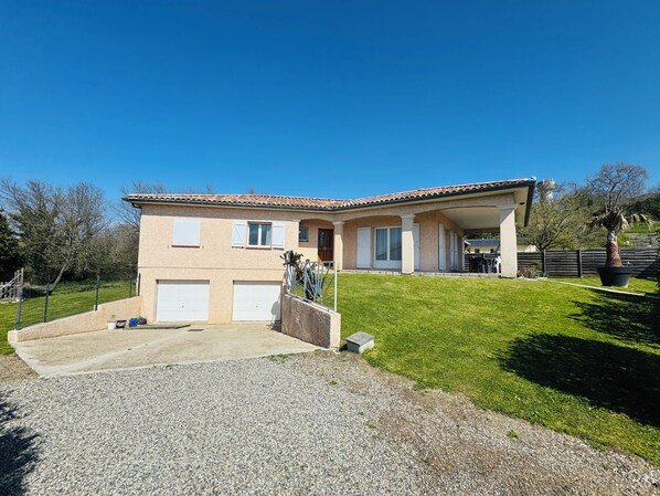 A two-story house with a covered porch, a gravel driveway, and a well-maintained lawn. - Villa on the ramparts with a terrace and a view of the Pyrenees (Montaut)