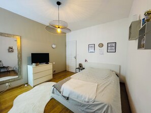A bedroom with a bed, a dresser, a television, a mirror, and a wall with framed pictures. - Villa on the ramparts with a terrace and a view of the Pyrenees (Montaut)
