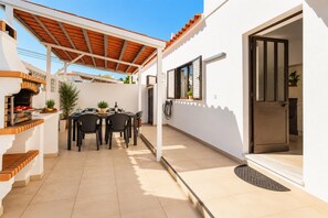 A covered outdoor dining area with a table and chairs, a grill, and a door leading to an interior space. - Villa Lela - Two Bedroom Villa, Sleeps 4 (Vale Rebelho)