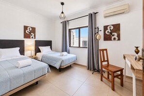 A hotel room with two beds, a desk, a chair, a lamp, and artwork on the walls. - Villa Lela - Two Bedroom Villa, Sleeps 4 (Vale Rebelho)