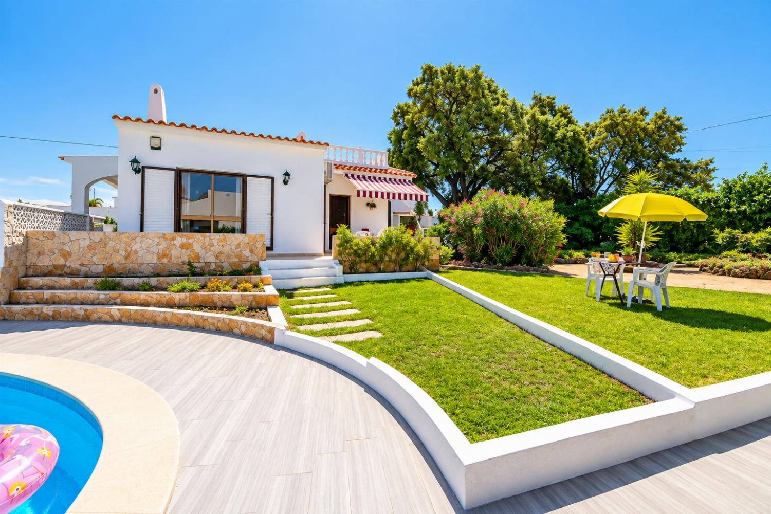 A modern house with a swimming pool, a well-maintained lawn, and a patio area with outdoor furniture.