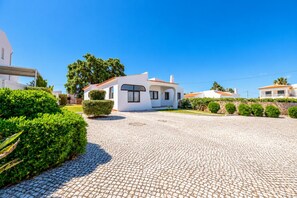A residential property with a paved driveway, white exterior walls, and a well-maintained garden. - Villa Rosa dos Ventos (Vale Rebelho)