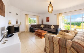 A living room with a sofa, a coffee table, a TV, and a fireplace. - Villa Godinho - Five Bedroom Villa, Sleeps 10 (Albufeira)