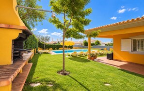 A backyard with a swimming pool, a barbecue area, and a patio with lounge chairs. - Villa Godinho - Five Bedroom Villa, Sleeps 10 (Albufeira)