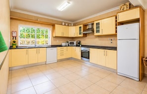 A kitchen with yellow cabinets, a white refrigerator, a microwave, an oven, and a dishwasher. - Villa Godinho - Five Bedroom Villa, Sleeps 10 (Albufeira)