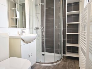 A modern bathroom with a glass-enclosed shower, a white sink, and a tiled shower area. - Ok31 Family Chalet (Oostkapelle)