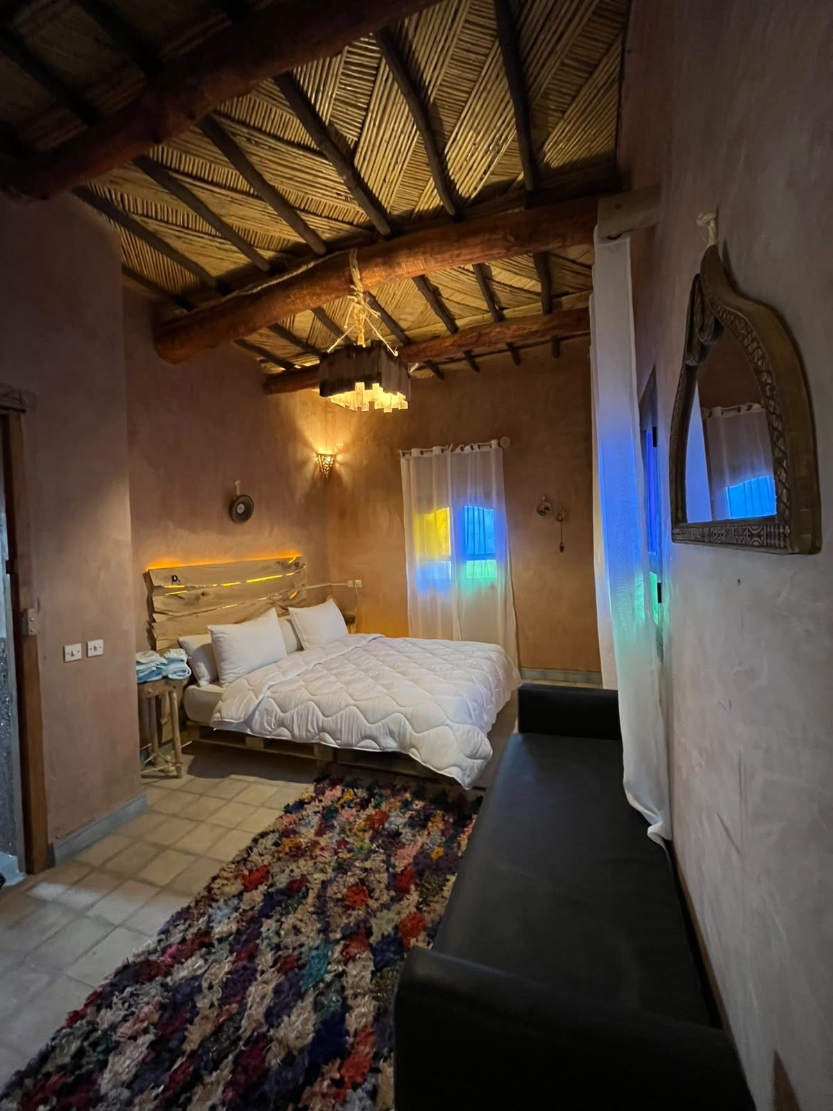Een slaapkamer met een bed, nachtkastje en een bankje.