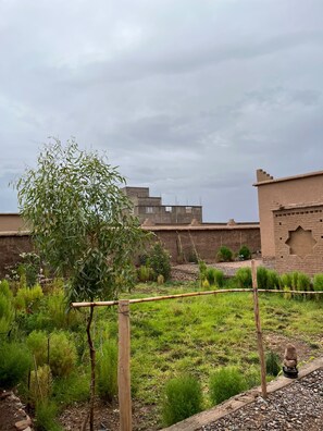 A garden with a variety of plants and a bamboo fence. - Zaim Heritage Kasbah (Skoura)