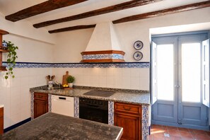 Une cuisine équipée d’un four encastré, d’un évier et d’une cuisinière. On y trouve également un meuble en bois et un plan de travail.