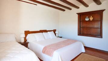 Un dormitorio con una cama doble, una mesita de noche, una lámpara de noche y un estante de madera con objetos decorativos.