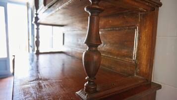 A wooden table with a carved leg, part of a room with a wooden wall and a door in the background.