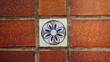 Un mur recouvert de carreaux, avec un seul carreau décoratif présentant un motif floral bleu et blanc.
