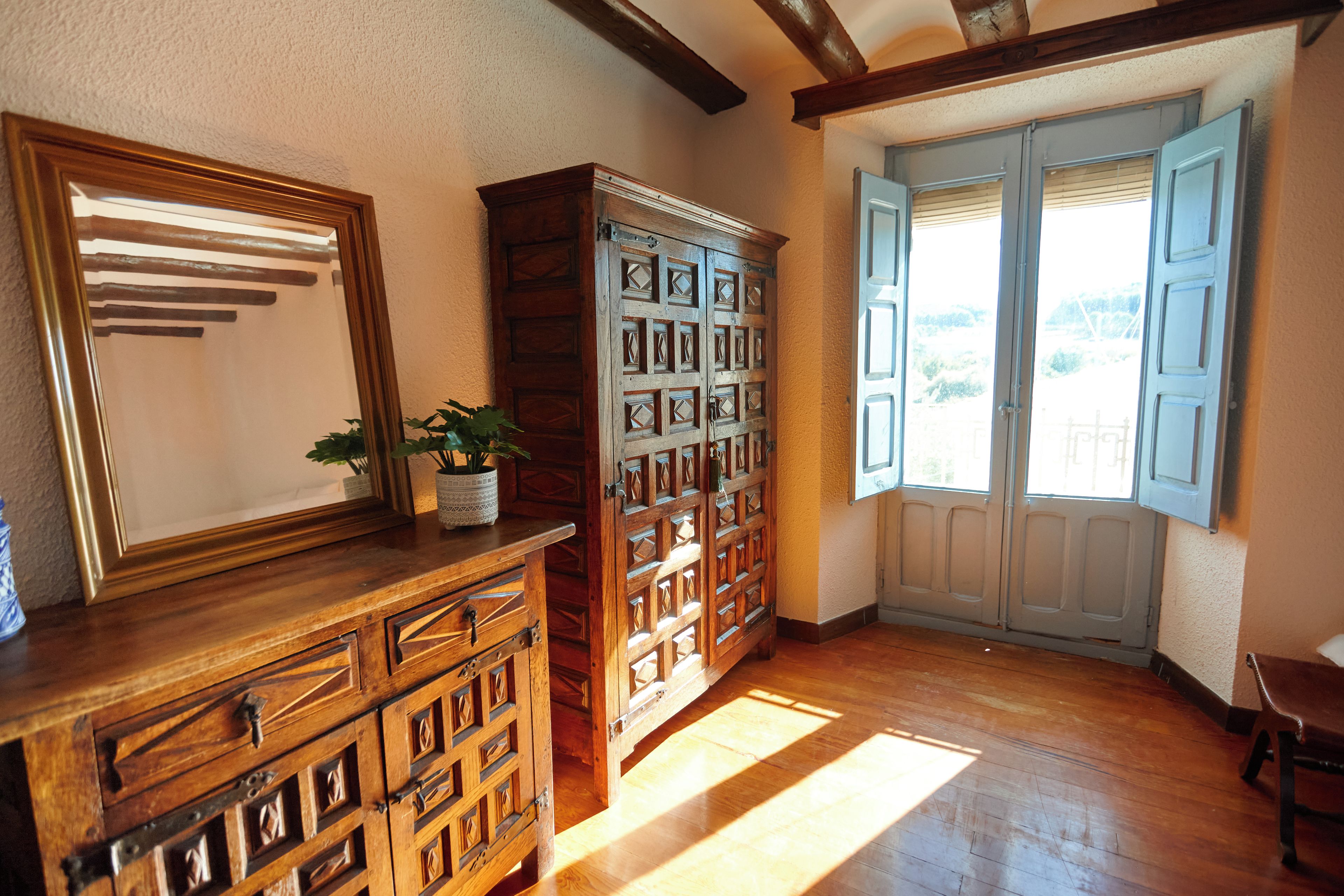 Una habitación con muebles de madera, un espejo grande y una ventana con persianas.