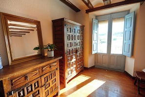 A room with wooden furniture, a large mirror, and a window with blinds.